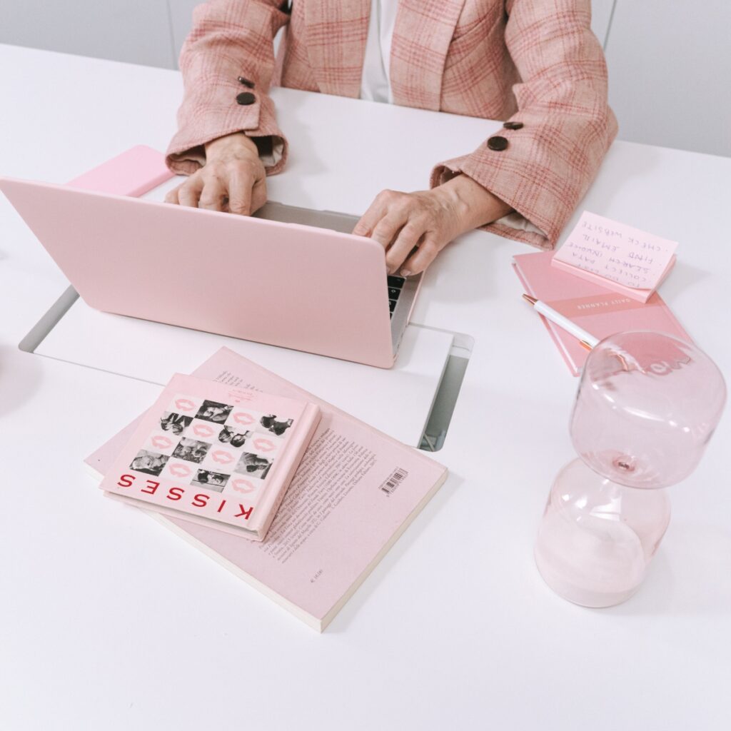 Blogging contracts on a pink feminine laptop with desk accessories.