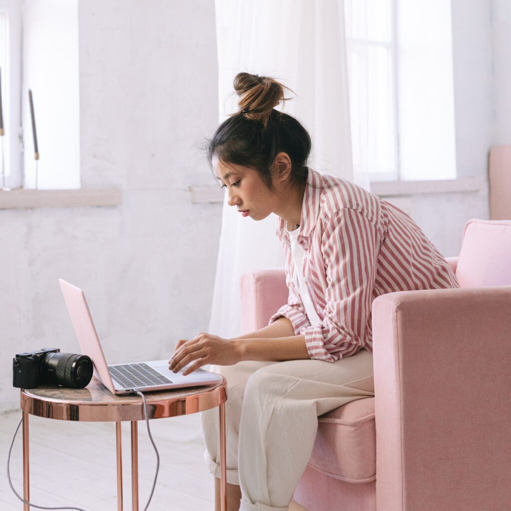 Woman in a pink chair reading a blogger contract from a laptop.