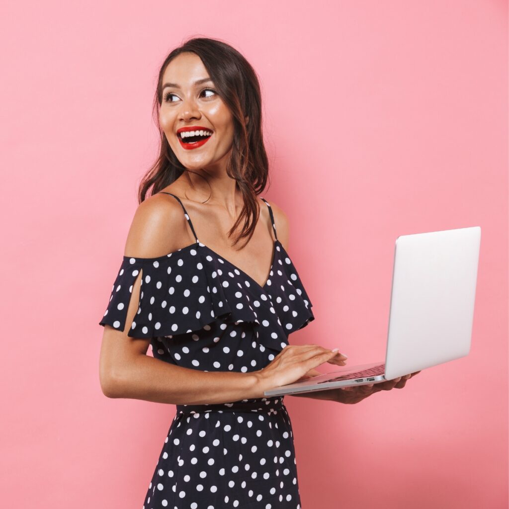 Woman in a polka dot dress holding a laptop.