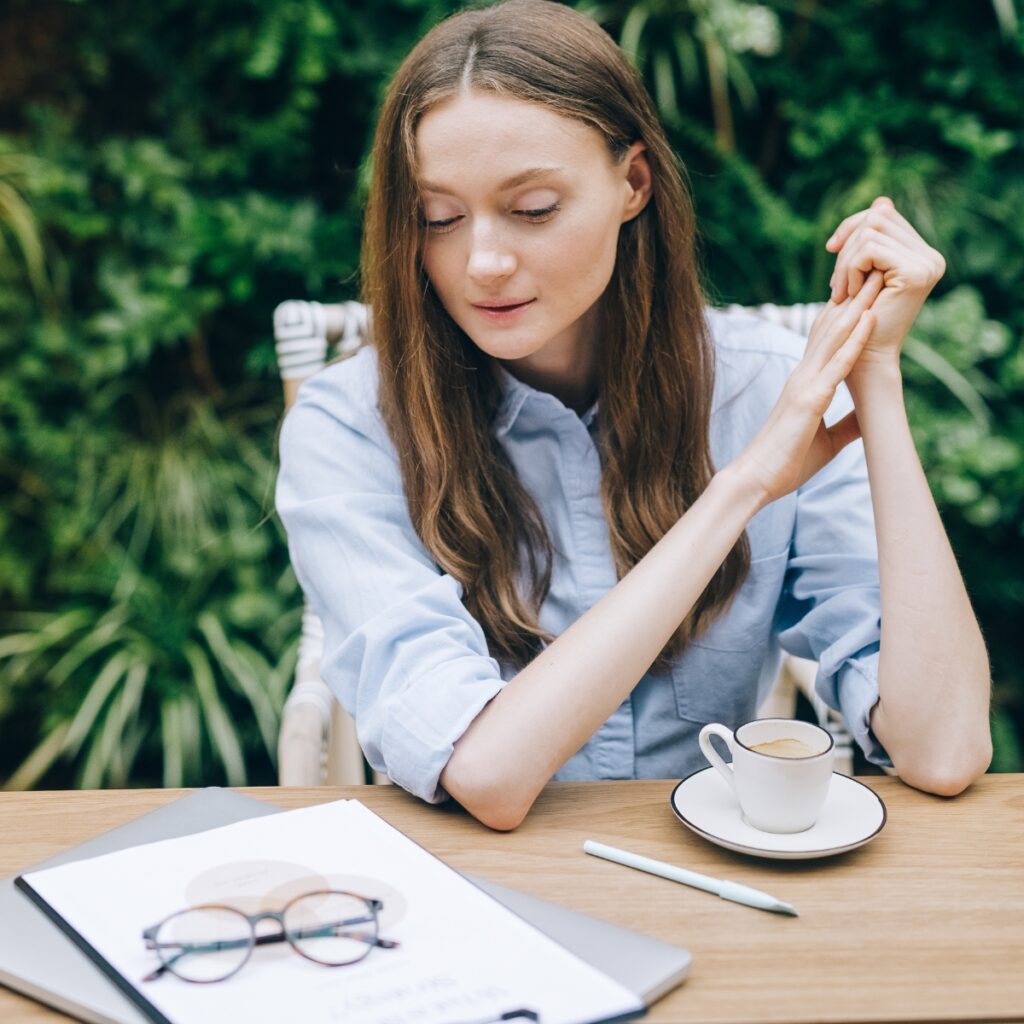 Woman deciding how to build a brand online with office supplies and coffee.